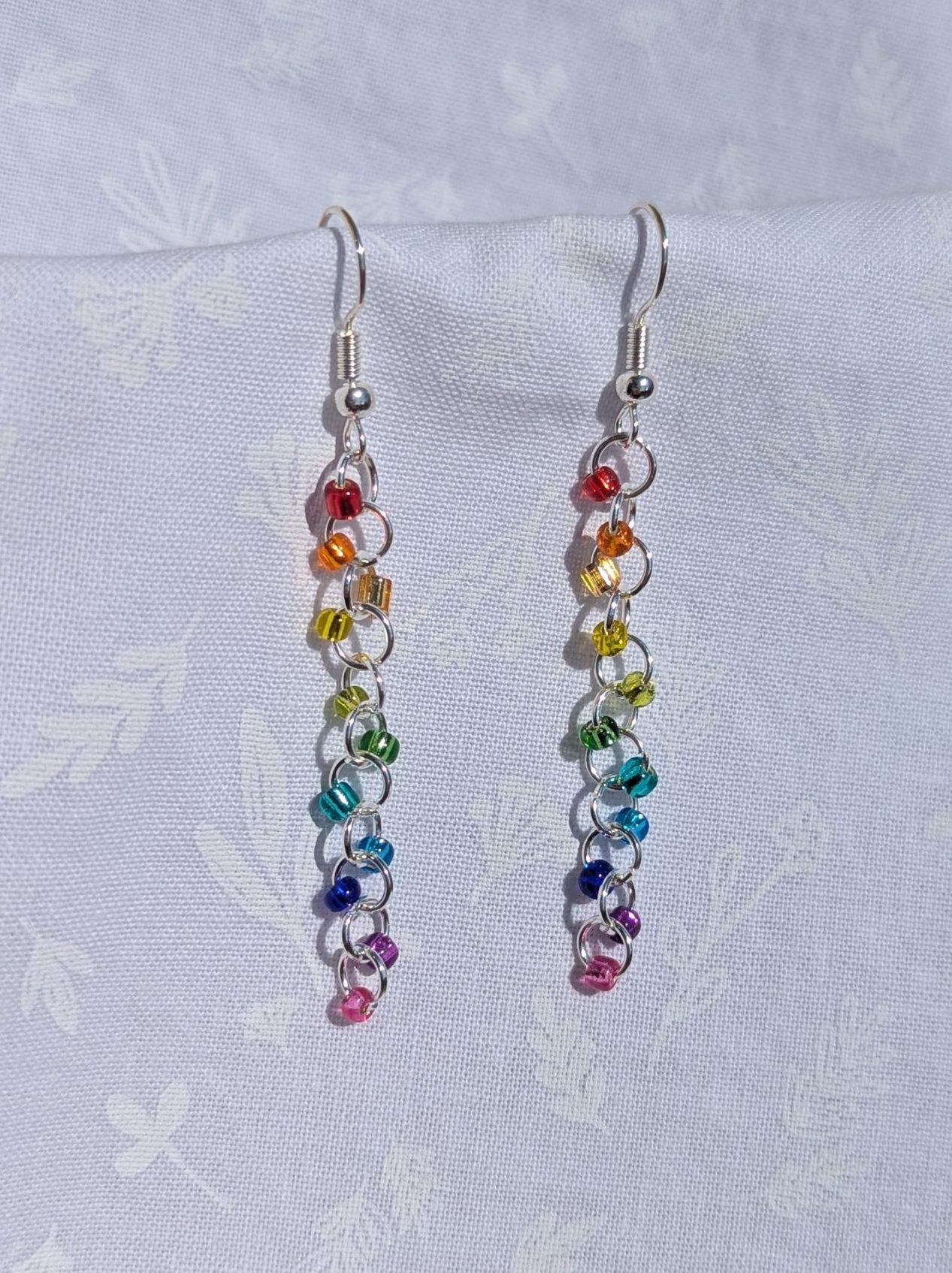 Silver Lining Rainbow earrings feature 11 different colored glass beads, all silver lined transparent. The beads are connected with silver colored jump rings.