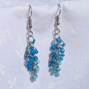 Blue beaded earrings with six different shades of blue glass seed beads, steel-colored jump rings, and steel earring hooks.