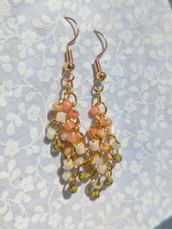 Spring is coming earrings feature pink, cream, and pale green beads with gold jump rings.