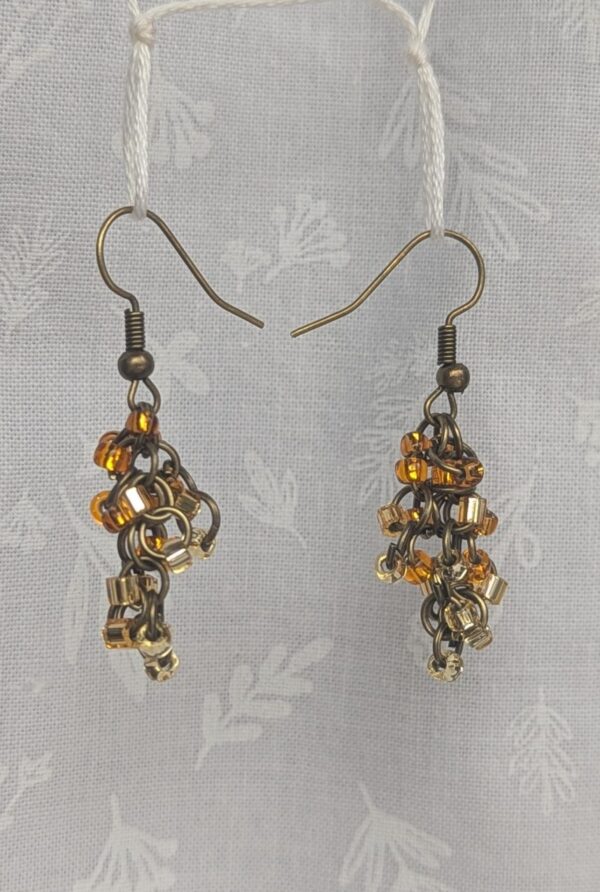 Earthy Brown beaded earrings feature four different hues of brown with various textures. Total of 12 beads per earring with 3 beads per color. Materials: glass seed beads, brass colored earring hooks, and brass colored jump rings.