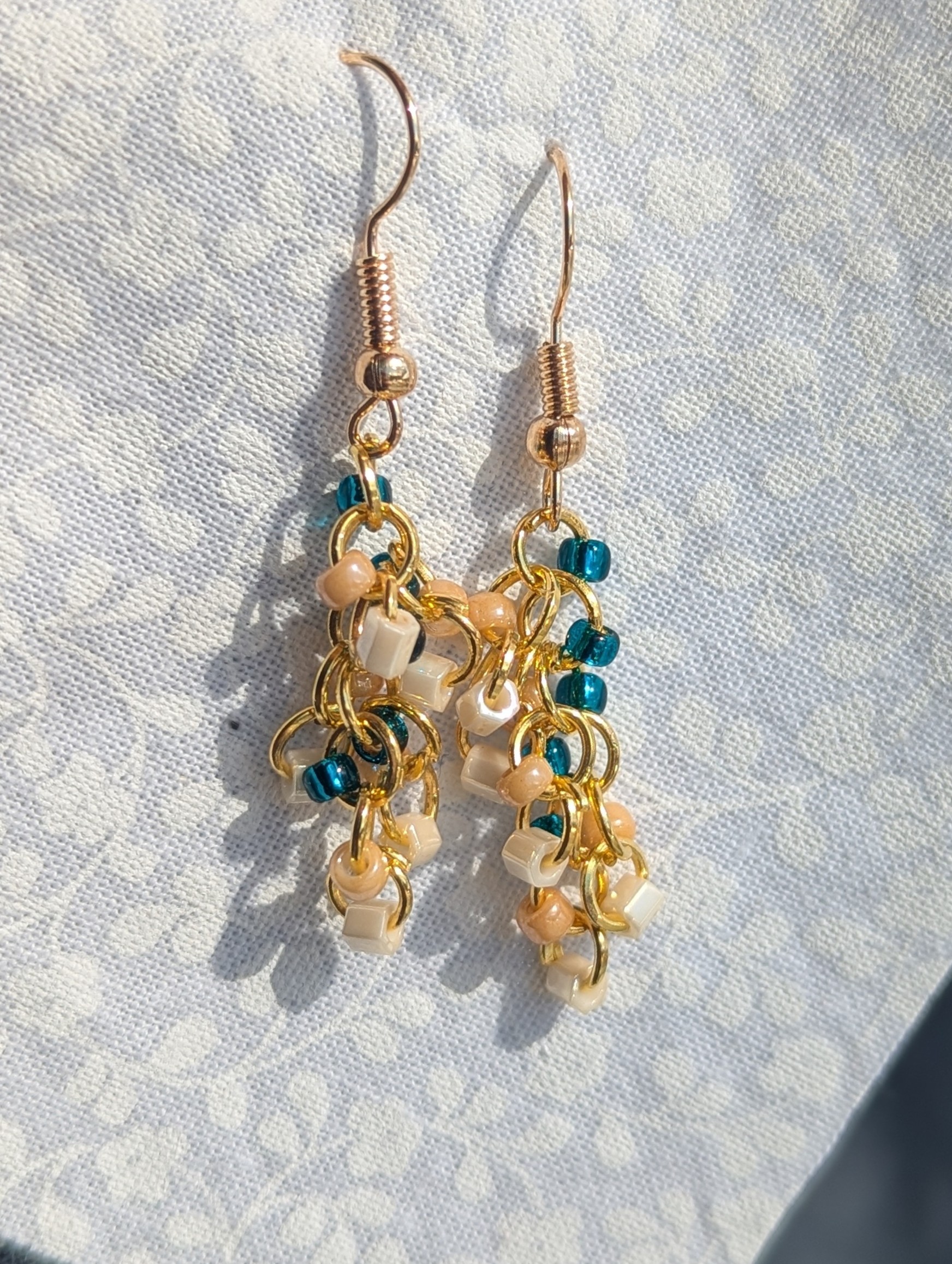 Spring Garden earrings feature teal. pink and cream glass seed beads with golden jump rings.