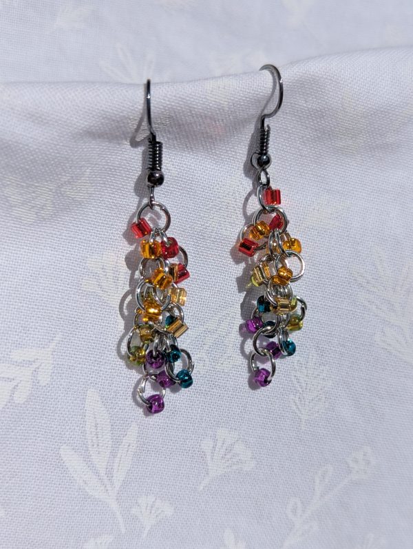 Rainbow Radiance Earrings: Colorful red, orange, yellow, green, teal, and purple beaded earrings with silver-lined beads, featuring pewter-colored hooks and jump rings.