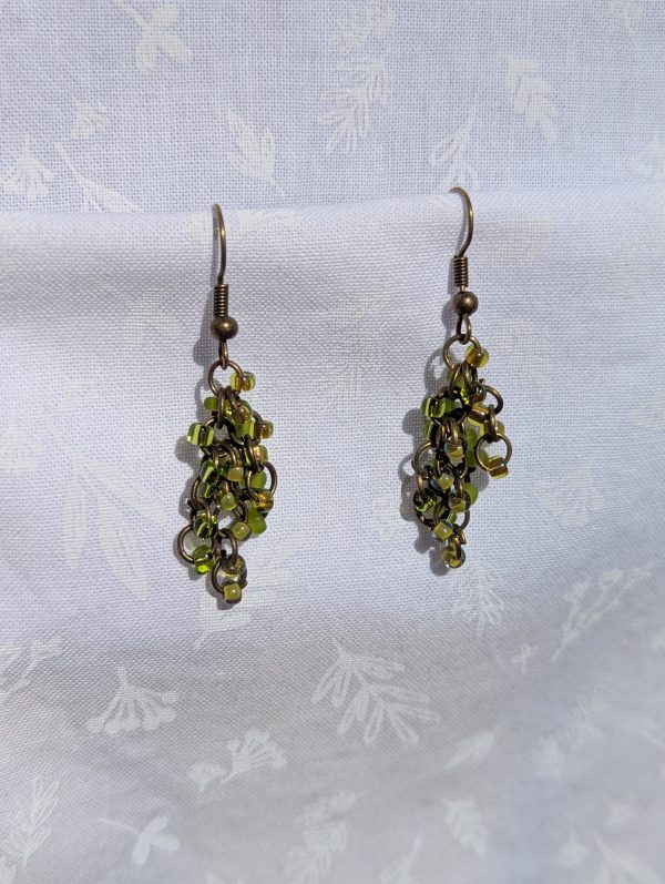 A pair of long, dangling green beaded earrings featuring 20 colorful glass seed beads per earring, attached to bronze colored jump rings and earring hooks