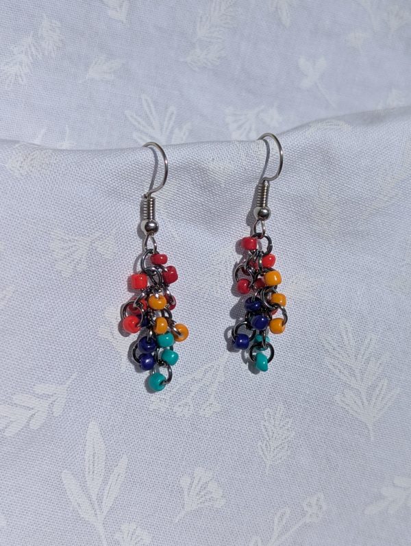 The Retro Rainbow Cascade Earrings feature colorful dark red, red, yellow, light blue, and dark blue beads with solid colors, pewter-colored jump rings and earring hooks.