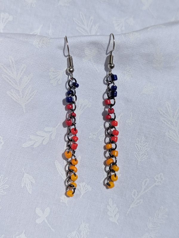 The Retro Cascade Long Earrings are long dark red, red, mustard yellow, yellow, and dark blue earrings with solid colors, featuring pewter-colored jump rings and earring hooks.