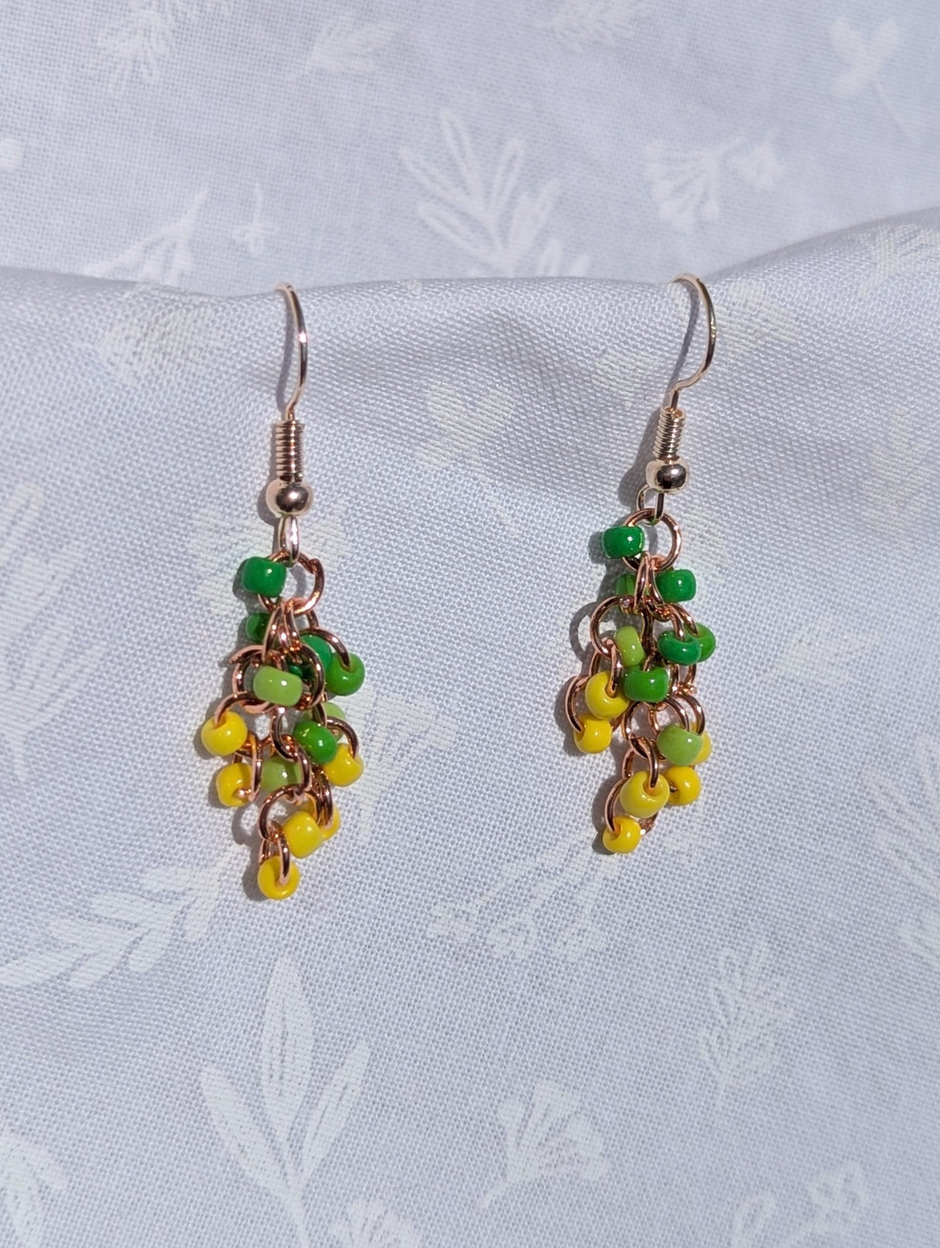 The Golden Grove Gradient Earrings feature a green and yellow gradient of glass beads, silver-colored hooks and copper jump rings.