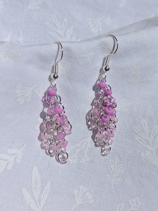 The Lavender Cascade Earrings feature a purple gradient of beads with five different hues and unique textures, silver-colored jump rings and earring hooks.