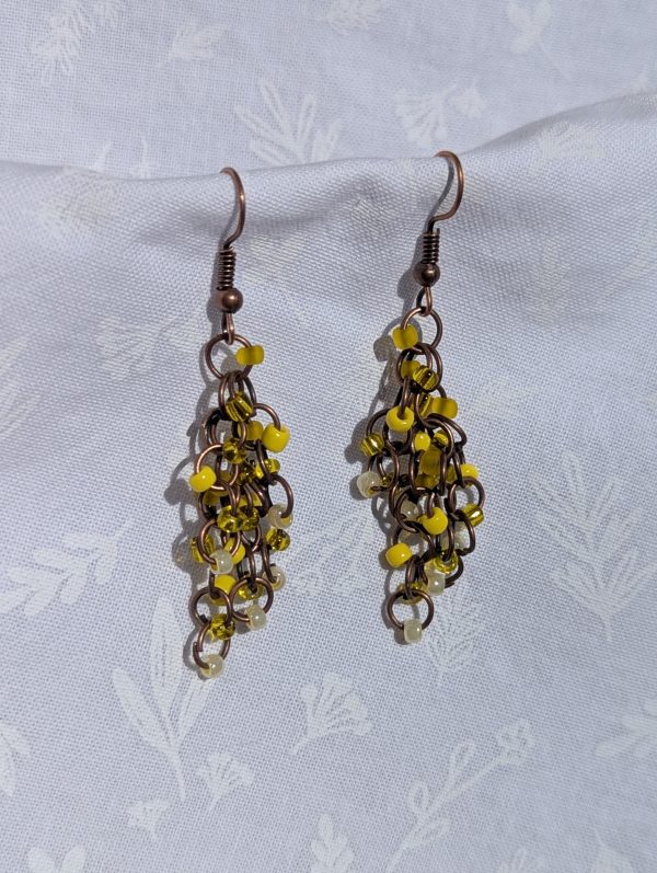 The Sunlit Rustic Earrings are Yellow and bronze earrings with five textured hues, featuring cascading bronze jump rings and earring hooks for a rustic, earthy design.