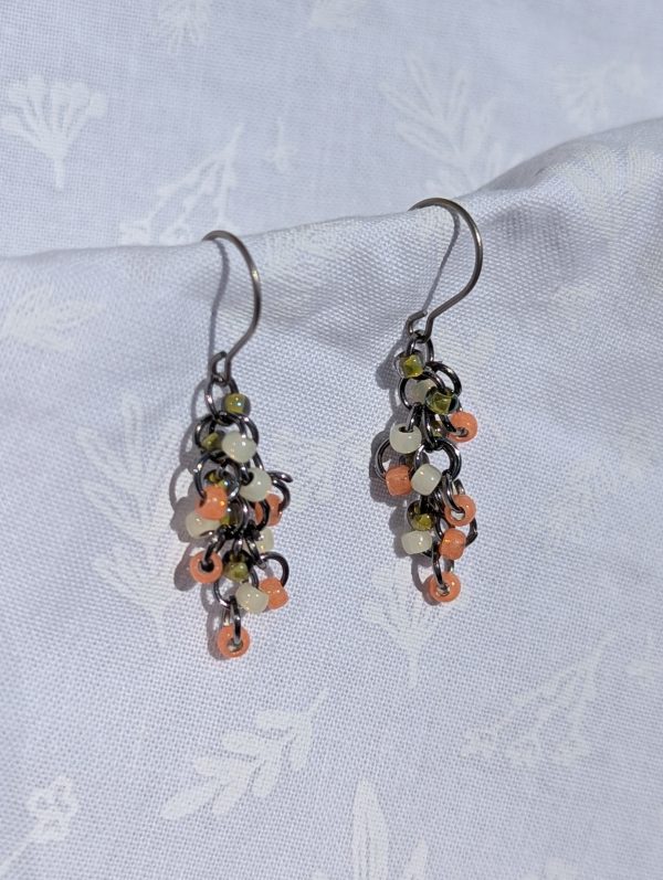 The Soft Blossom Earrings: Salmon, white, and green earrings with textured glass beads, featuring pewter-colored jump rings and titanium hooks for a delicate, cascading design.