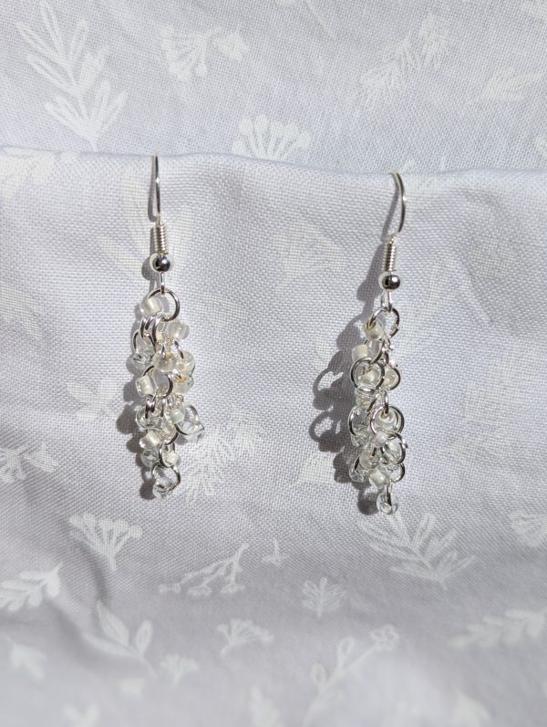 These Glittering Ice Earrings have three hues of white and clear glass beads, 18 in total, in a cascading arrangement with contrasting textures.