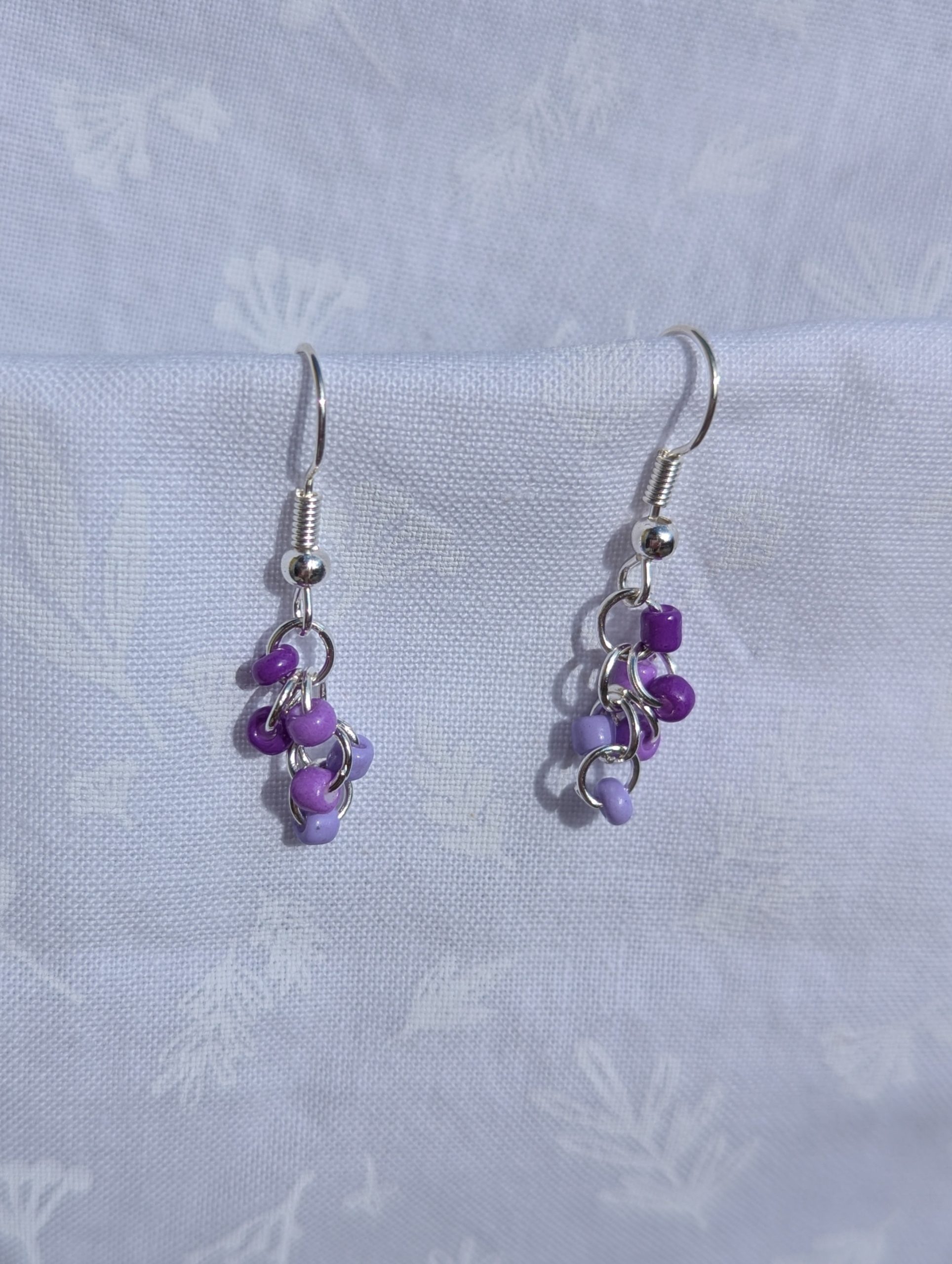 These elegant purple drops earrings feature nine purple glass seed beads per earring in three shades.