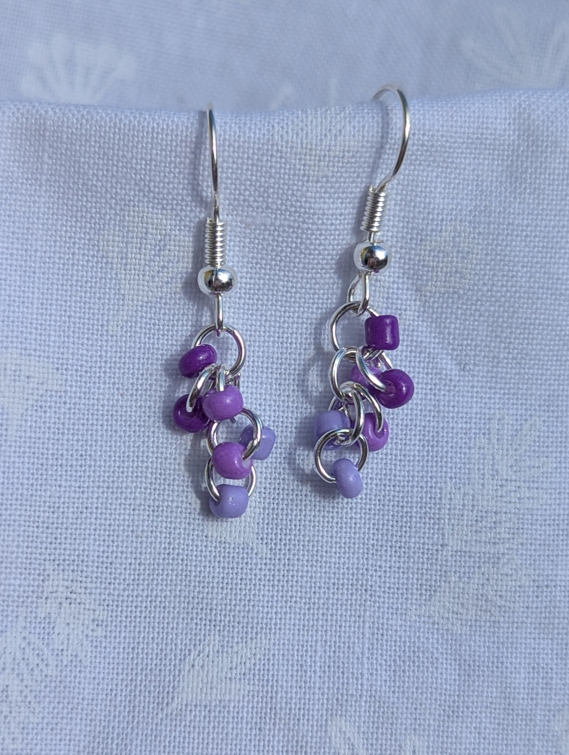 These elegant purple drops earrings feature nine purple glass seed beads per earring in three shades.