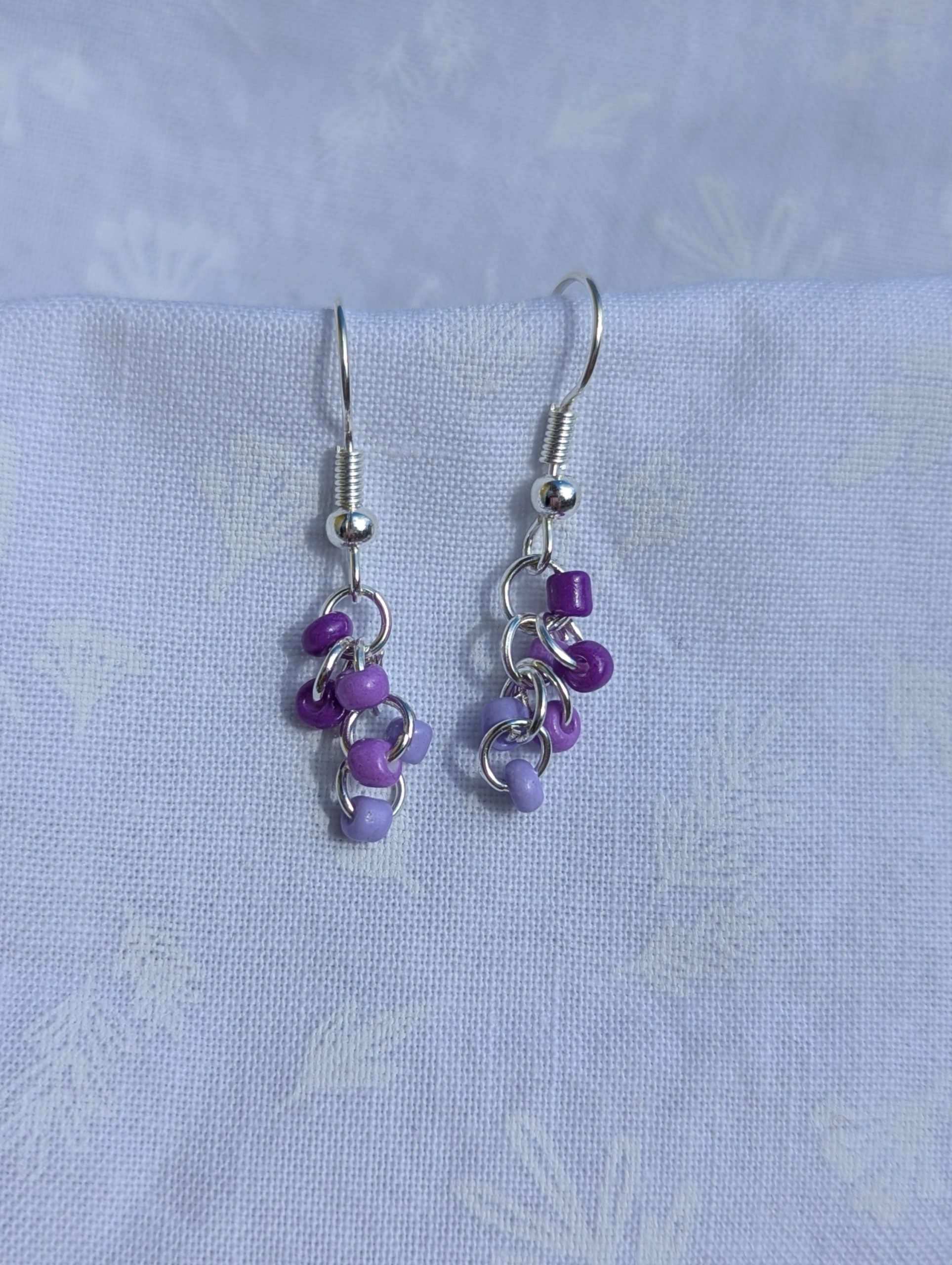 These elegant purple drops earrings feature nine purple glass seed beads per earring in three shades.
