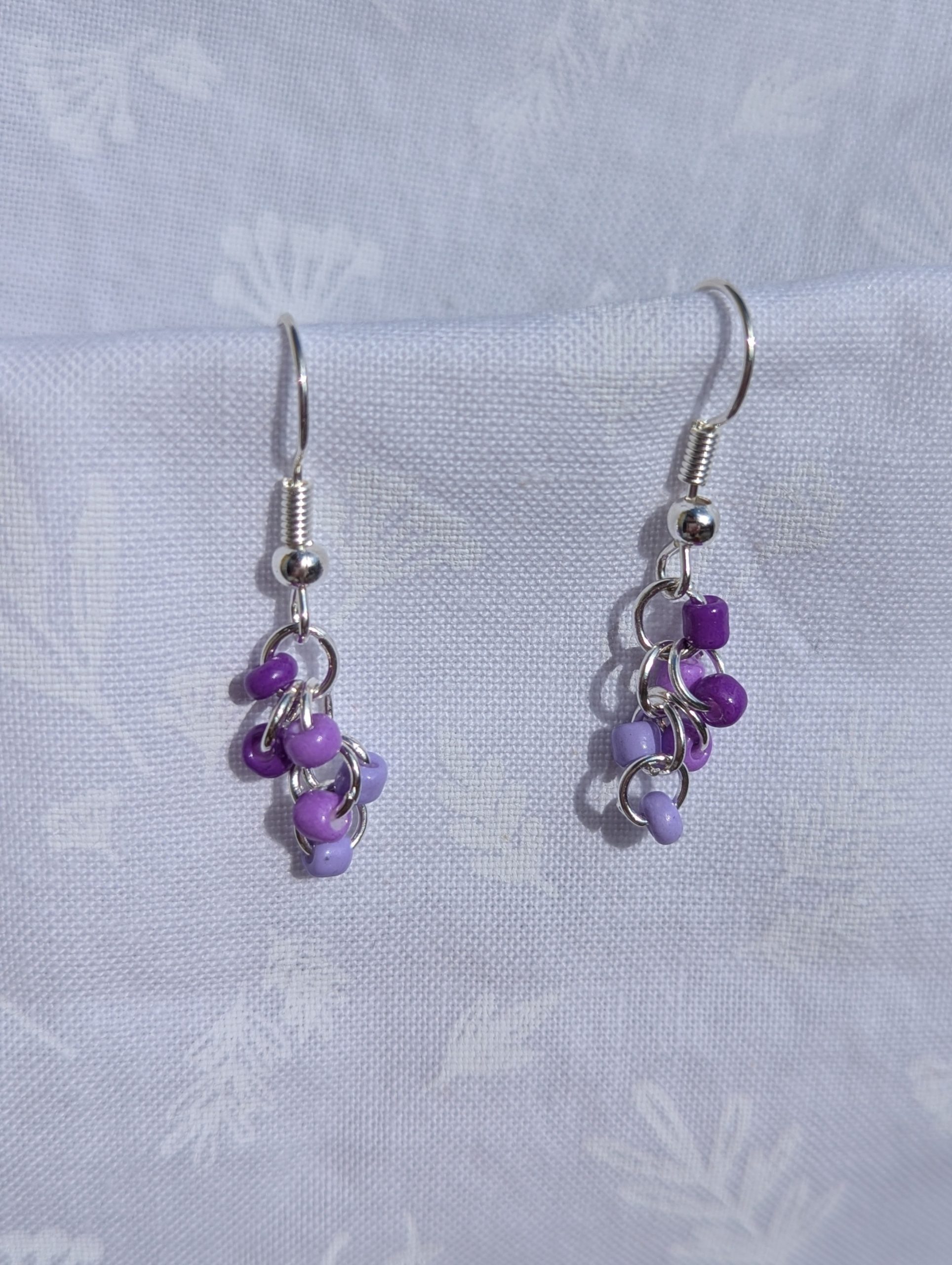 These elegant purple drops earrings feature nine purple glass seed beads per earring in three shades.