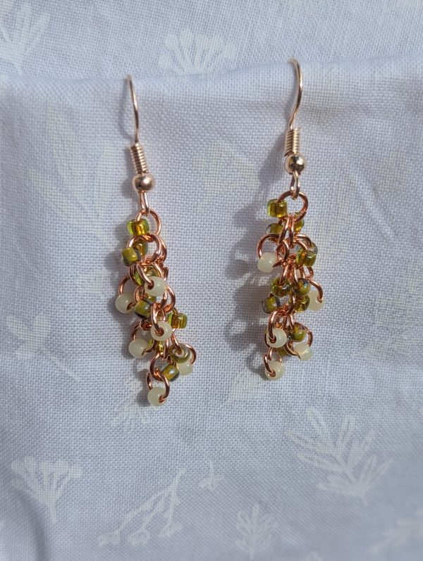 These vibrant Spring Meadow Earrings feature a stunning blend of grass green, pale yellow, and cream glass seed beads with a variety of textures. A total of 18 beads per earring—six beads per color—cascade gracefully, creating a vibrant and eye-catching effect.
