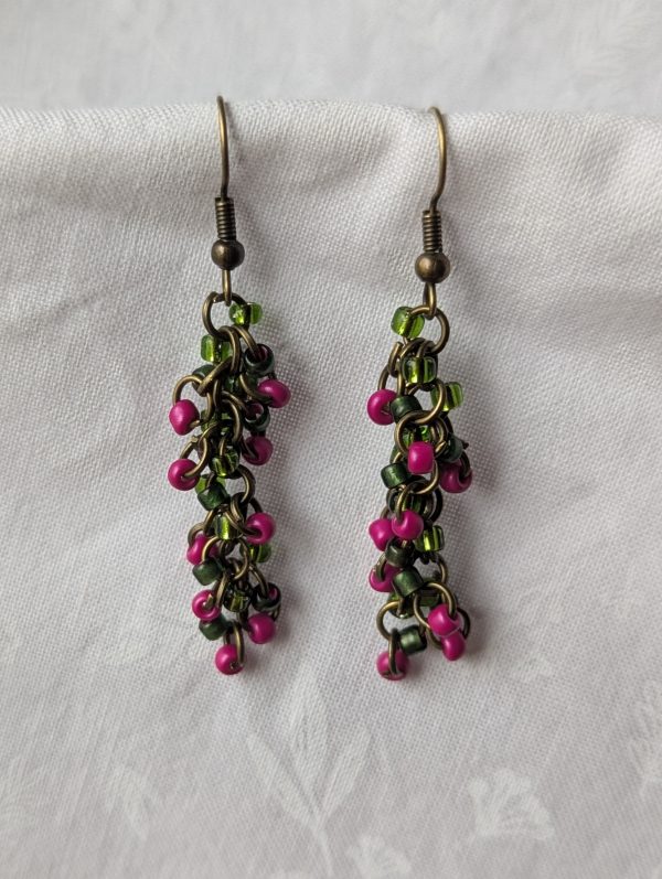Enchanted Garden Earrings: Handmade earrings featuring deep green, deep fuchsia, and fuchsia-lined green beads, intricately connected with bronze jump rings and matching hooks.