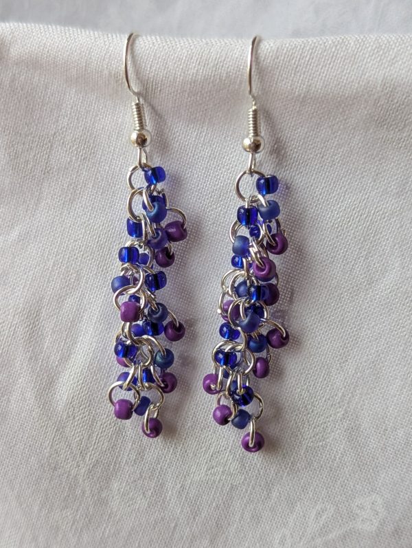 Twilight Reverie Earrings: Handmade earrings featuring deep purple, matte purple-blue, and silver-lined deep blue beads, connected with bronze jump rings and matching hooks.
