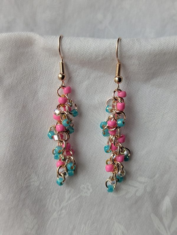 Colorful Unicorn Vomit earrings featuring cotton candy pink, pearly cyan blue, and silver-lined clear beads, connected with rose-gold jump rings and matching hooks.
