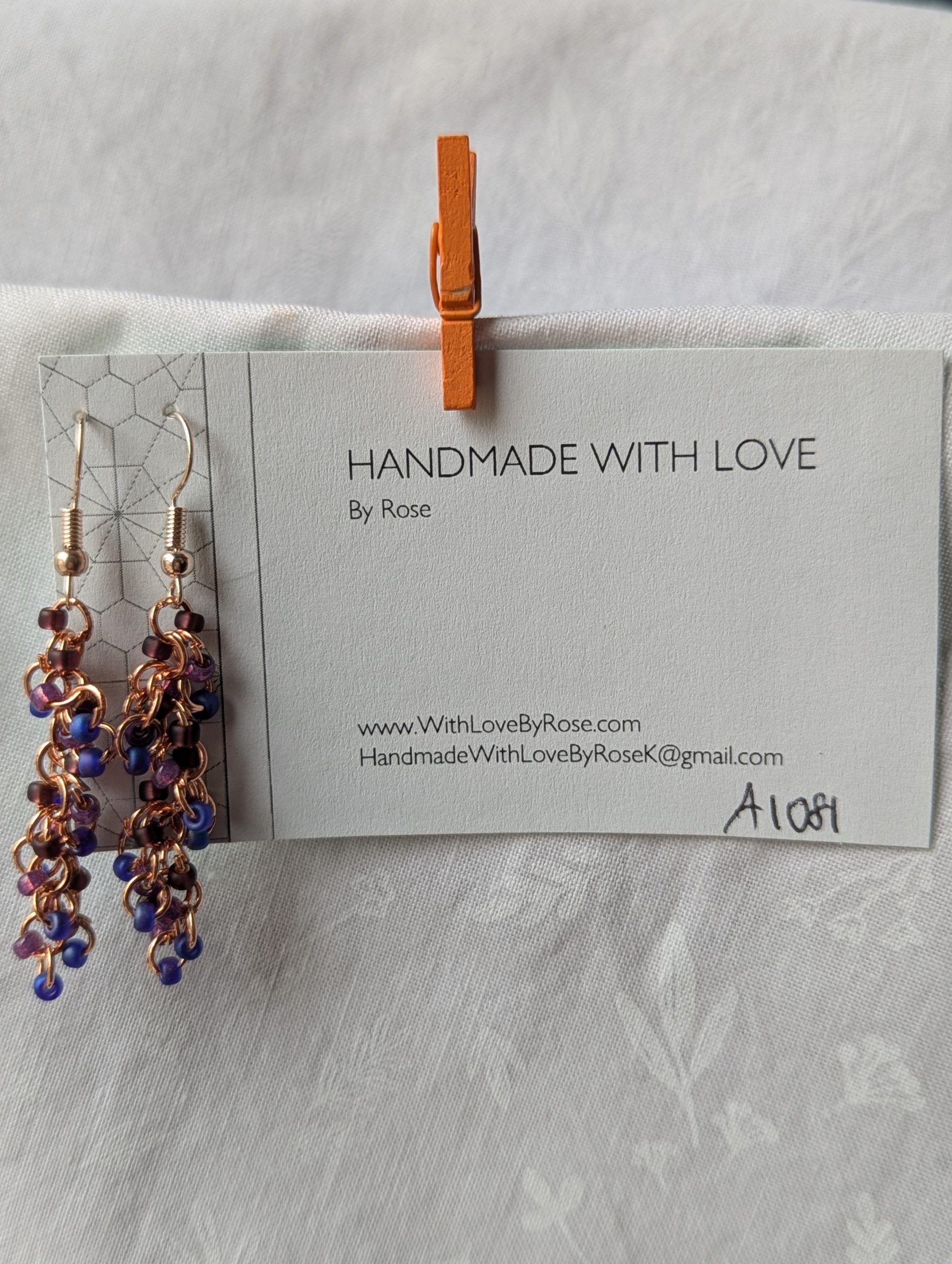 Dragon Scales Earrings featuring iridescent blue/purple, matte deep purple, and pearly amethyst beads, connected with rose-gold jump rings and matching hooks.