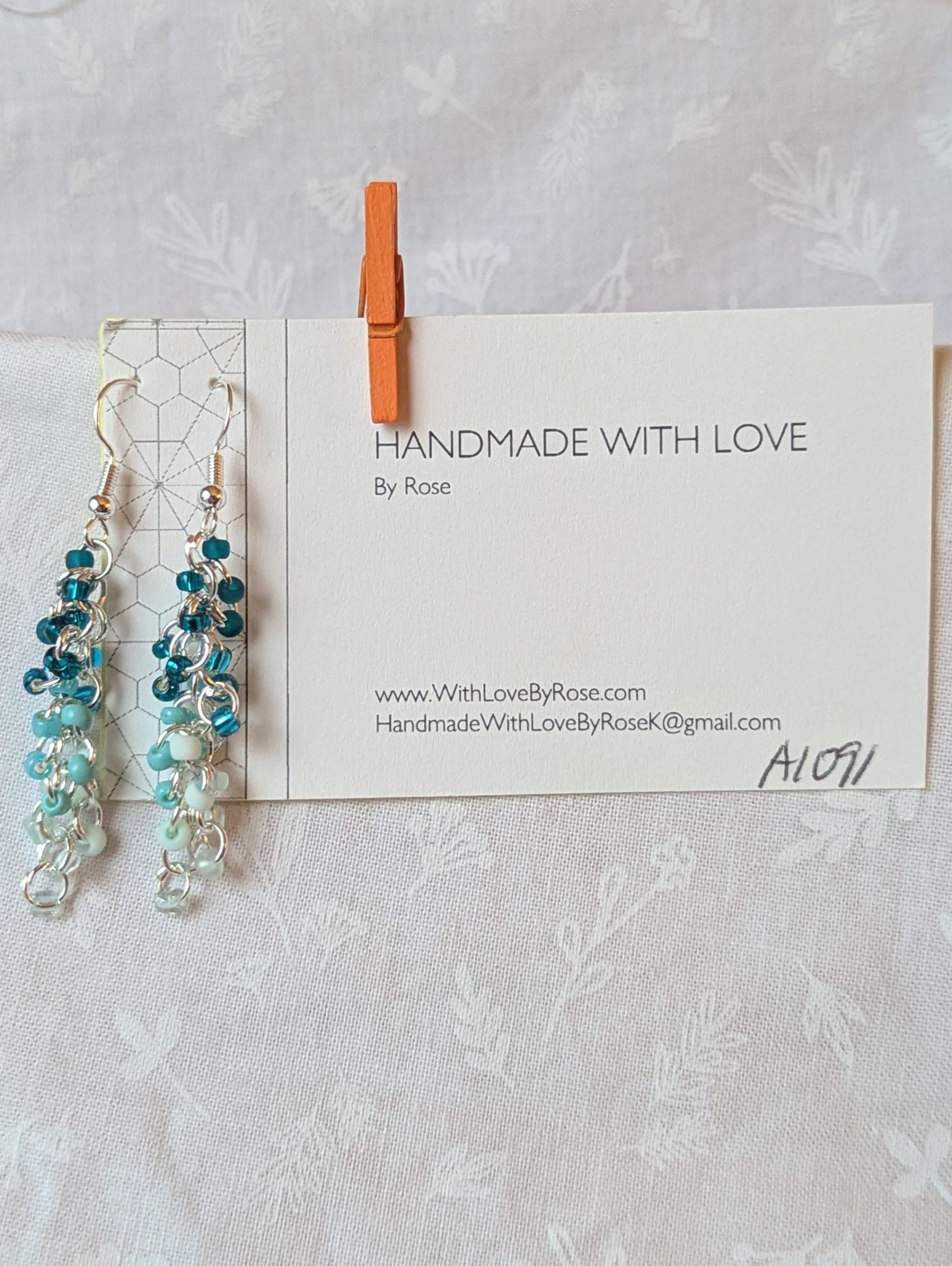 Caribbean Sea earrings with 27 beads in nine teal and cyan shades, including frosted, pearly, and translucent finishes. Connected with silver-colored jump rings and earring hooks.