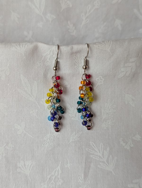 Muted Prism Glow Earrings with 24 frosted glass beads in rainbow colors, including red, orange, yellow, seafoam green, teal, cyan, blue, and purple. Assembled with steel-colored jump rings and earring hooks.