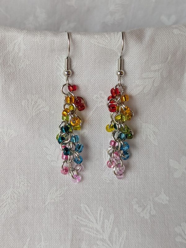A pair of handmade dangle earrings featuring 24 transparent glass beads in rainbow colors, hanging from silver-colored jump rings and earring hooks.