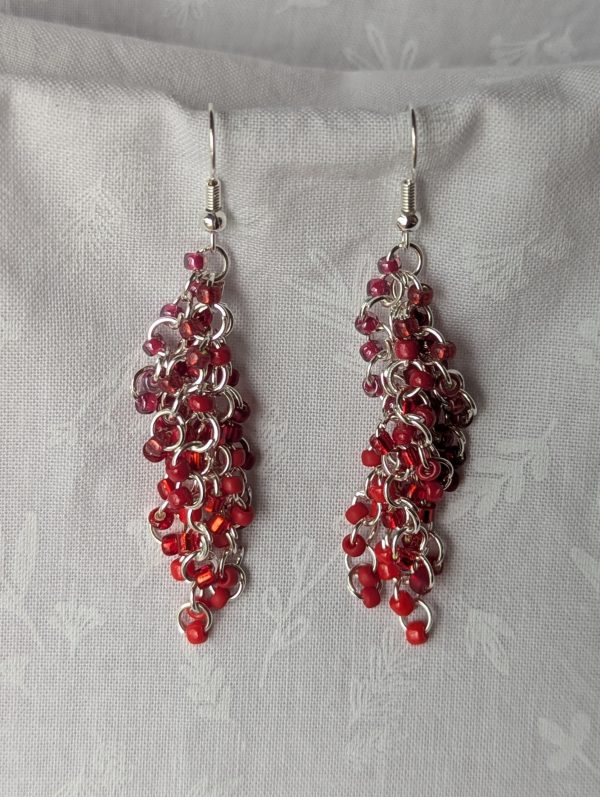 Red Rhapsody Earrings with 56 bright red beads in 9 textures and shades, connected by silver jump rings and matching hooks.