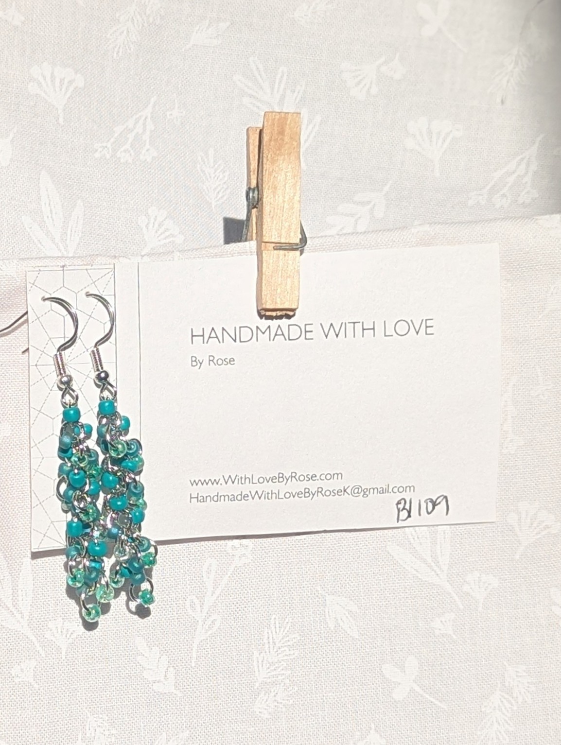 Forest Whispers — Handmade earrings with 27 green beads in shimmering, solid, and green-lined clear tones, connected with steel-colored jump rings and matching hooks.