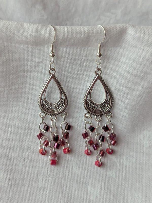 Crimson chandelier earrings with Tibetan ornament, featuring garnet, wine, dark red lined clear, and candy apple red beads.