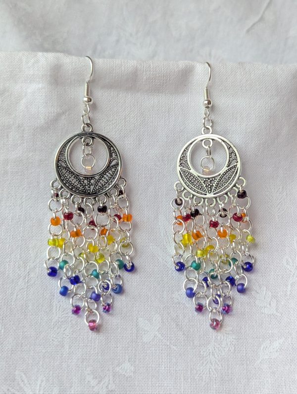 Celestial Rain earrings with colorful rainbow beads cascading from ornate silver celestial ornaments, connected with silver jump rings and earring hooks.