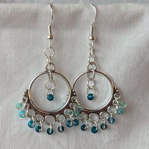 Aqua chandelier earrings with Tibetan ornaments, featuring beads in five oceanic hues including seafoam green, shimmering cyan, silver lined teal, gold lined teal, and frosted teal.