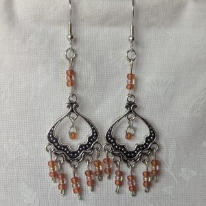 Blushing Elegance Chandelier Earrings feature a Tibetan ornament and 19 beads in frosted iridescent ballet pink and pale pink-lined clear.