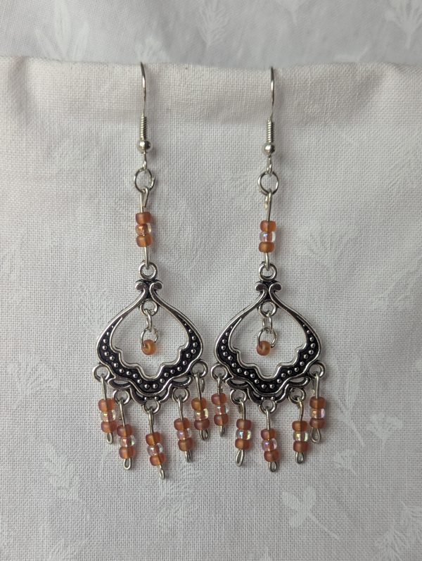 Blushing Elegance Chandelier Earrings feature a Tibetan ornament and 19 beads in frosted iridescent ballet pink and pale pink-lined clear.