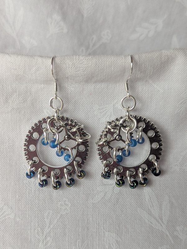 The Celestial Gears Earrings: Gear-themed earrings with 9 beads in frosted iridescent blue and iridescent metallic indigo, finished with silver-colored hooks.