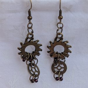 Crimson Cogs Earrings: Steampunk-style earrings with two bronze-colored gears and four silver-lined wine-colored beads, finished with bronze earring hooks.
