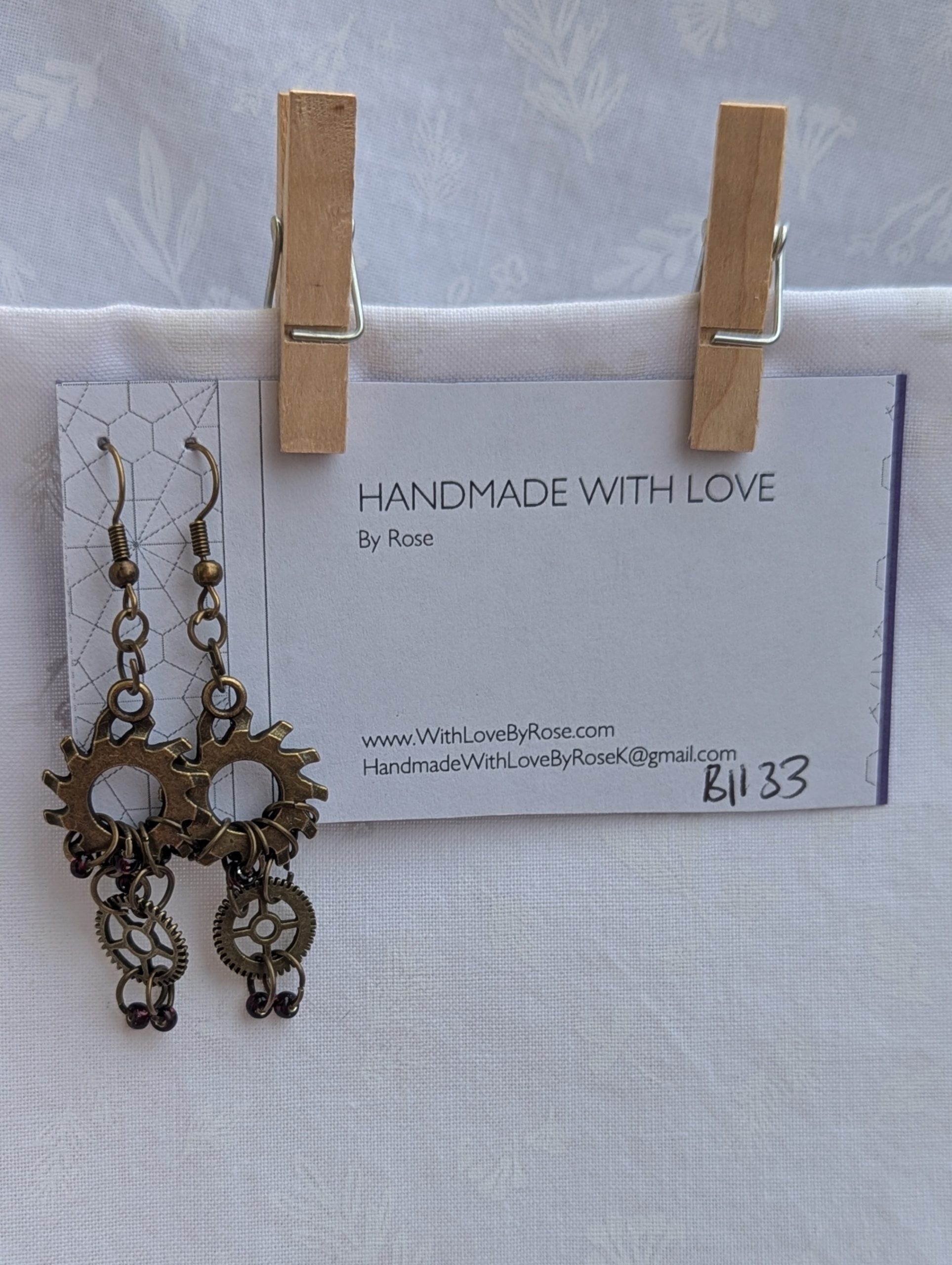 Crimson Cogs Earrings: Steampunk-style earrings with two bronze-colored gears and four silver-lined wine-colored beads, finished with bronze earring hooks.