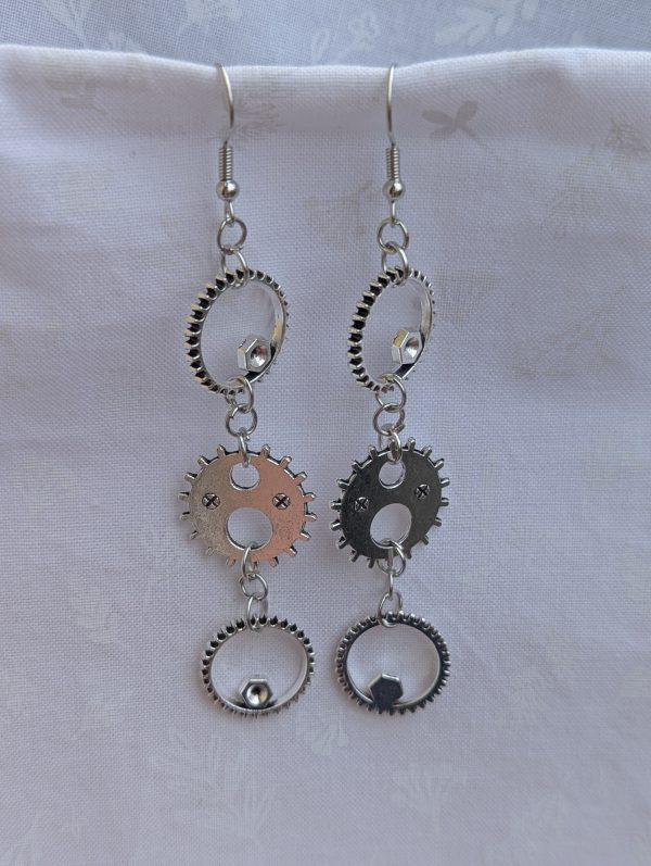 Industrial Elegance Earrings: Pair of silver-colored gear earrings with three interlinked gears, connected by silver jump rings and hung on silver earring hooks.