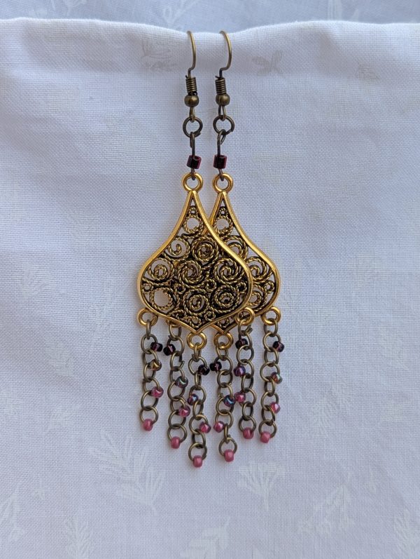 Gilded Ruby Cascade Earrings: Antiqued gold filigree earrings with five cascading bronze chains, each adorned with red-toned beads in multiple textures and finishes.