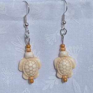 Desert Drift Turtle Earrings: Pair of earrings featuring beige turtle charms with tan and light brown beads on each side, connected by steel-colored findings.