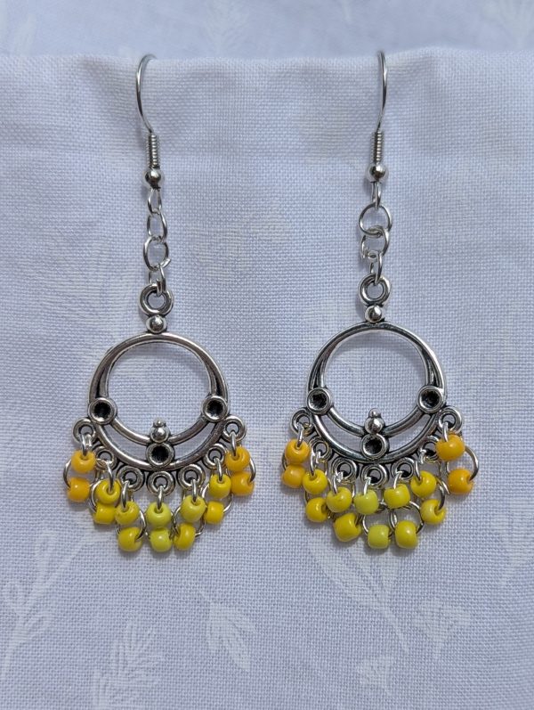 Sunspell Earrings: Silver circular filigree earrings with 14 dangling yellow beads in varied warm tones, including gold, marigold, and bright yellow, on steel-colored hooks.