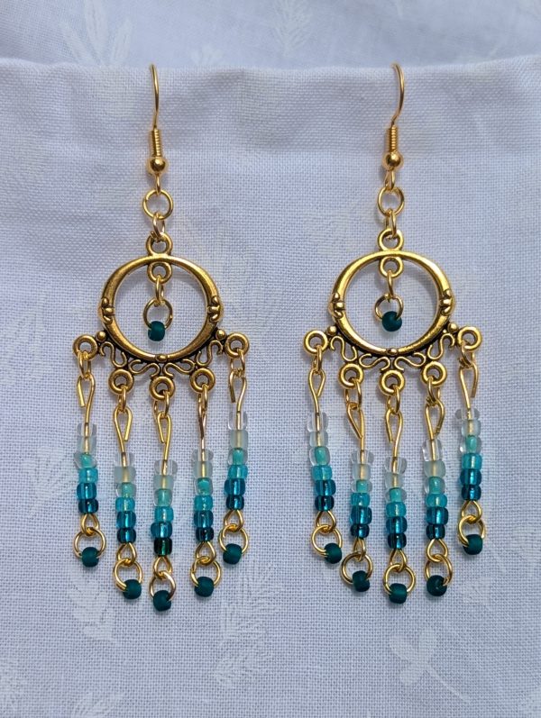 Ocean Depths Earrings: Gold circular earrings with 36 teal gradient glass beads in various textures, from seafoam to deep ocean tones.