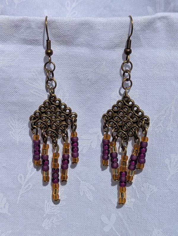 Saffron Twilight — Handmade bronze Tibetan-style earrings with 35 glass beads in plum, mulberry, gold-lined, and amber-gold tones.