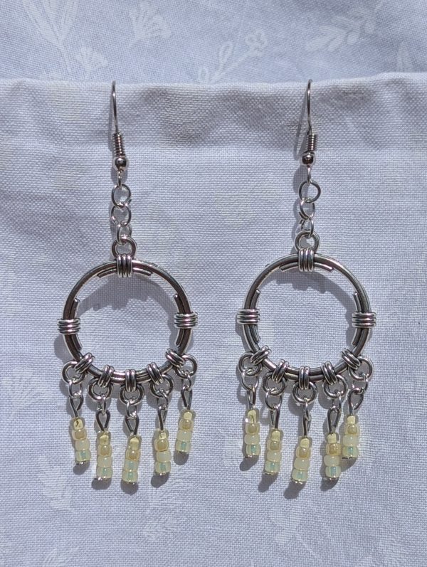 Lemon Meringue Glow — Silver hoop earrings with wrapped detailing and dangling pale yellow and champagne-toned glass beads in soft, translucent shades.