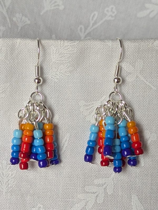 Fire and Ice Gradient Earrings – Gradient dangle earrings featuring 50 glass seed beads per earring in warm fire tones and cool ice hues, hung in strands from silver-colored posts with silver hooks.