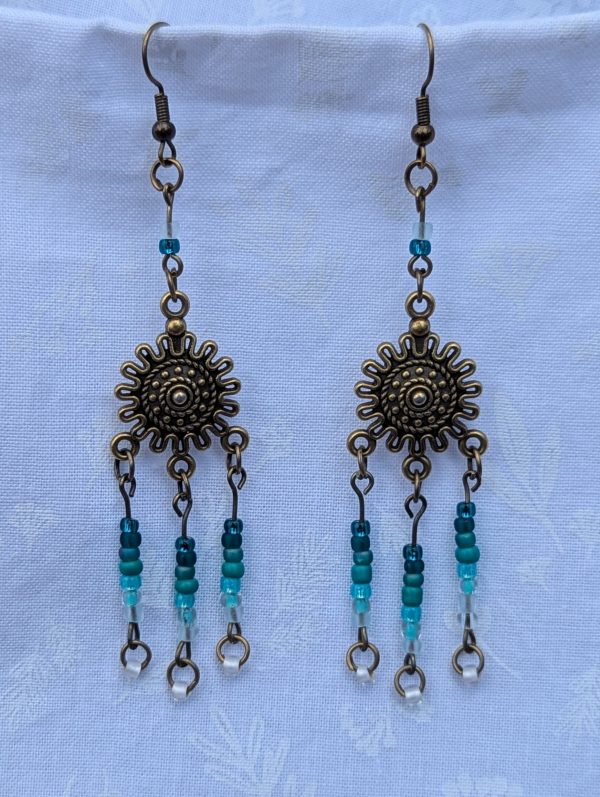 Sunburst Surf Earrings: Bronze sunburst earrings with hanging teal gradient beads in multiple shades.