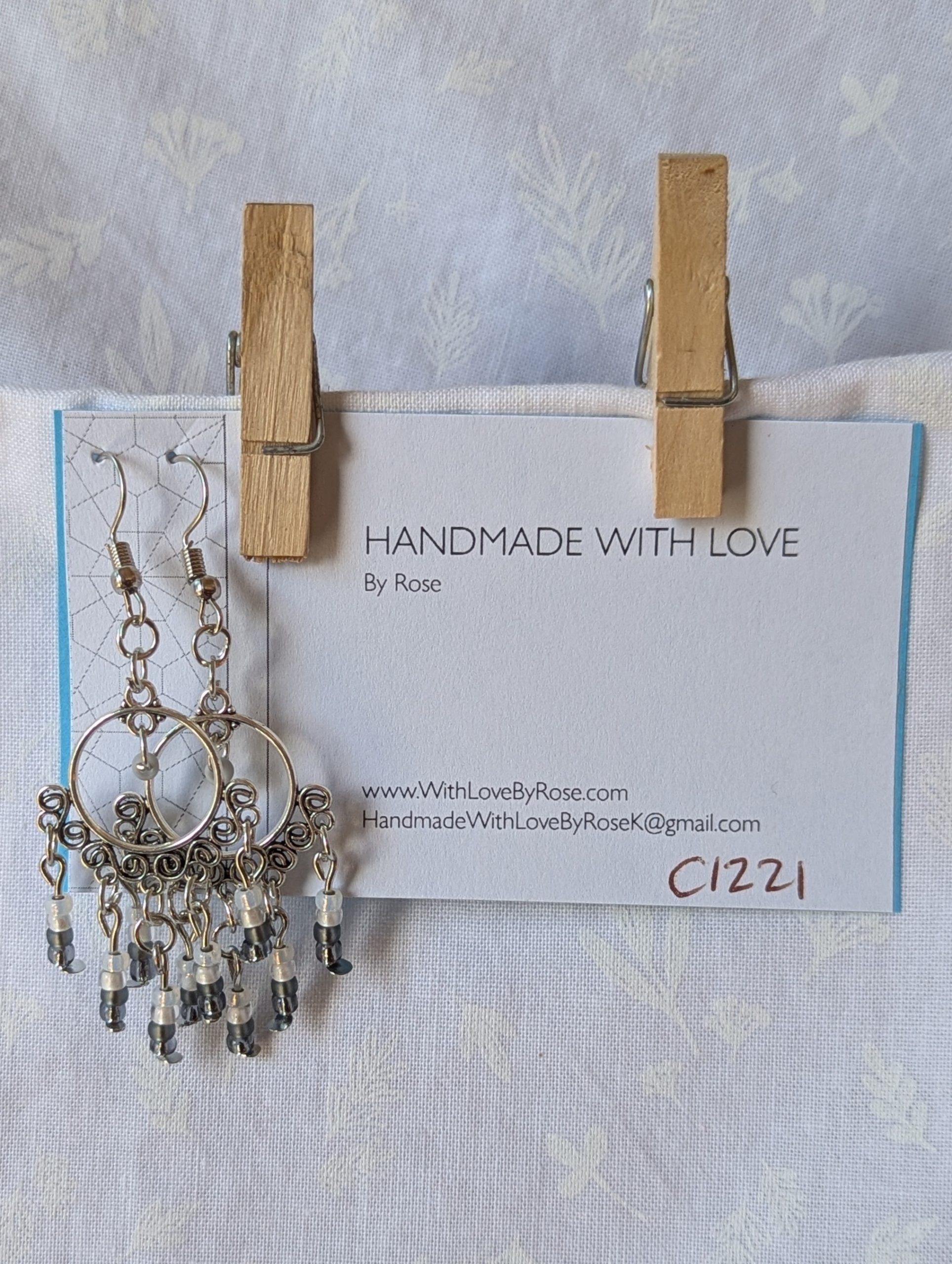 Pair of black and white earrings, handcrafted with silver crescent filigree hoops and dangling glass beads in a white-to-black gradient, including opal, frosted, matte, smoky, and black finishes. Hung on silver hooks.