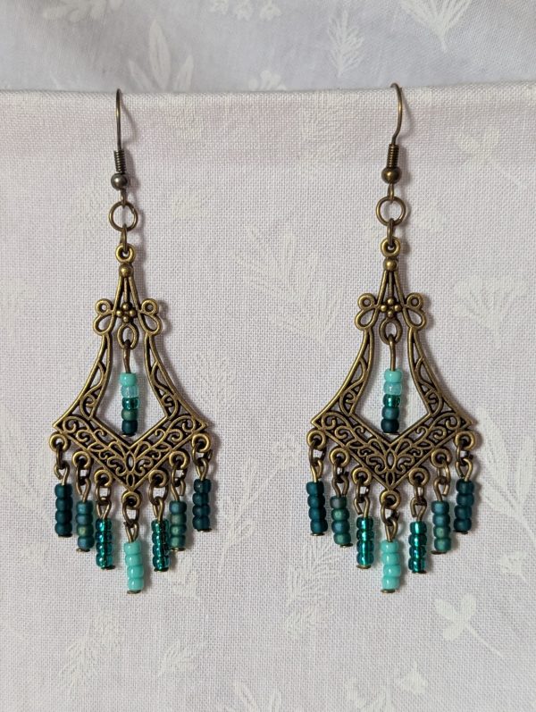 Teal Twilight Earrings with 29 teal glass beads in four ocean-inspired hues, hanging from ornate bronze filigree ornaments and bronze hooks.