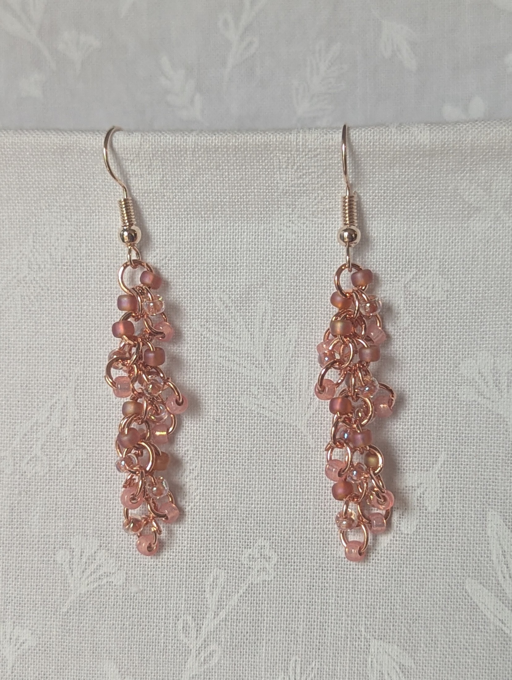Blush Bloom Earrings with 27 soft pink glass beads in matte, translucent, and iridescent finishes, on copper rings with rose-gold earring hooks.