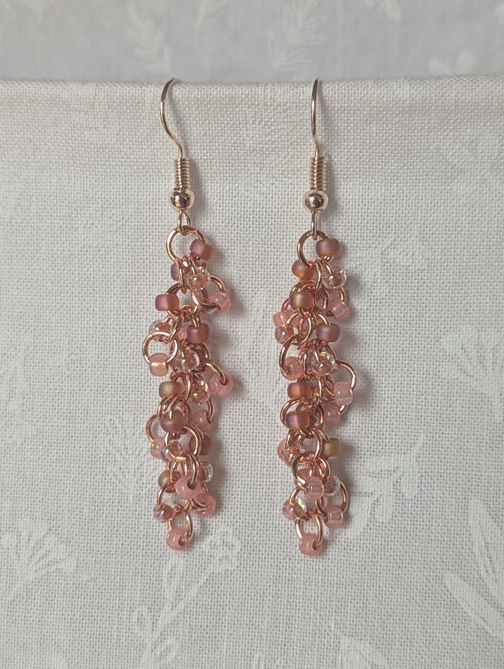 Blush Bloom Earrings with 27 soft pink glass beads in matte, translucent, and iridescent finishes, on copper rings with rose-gold earring hooks.