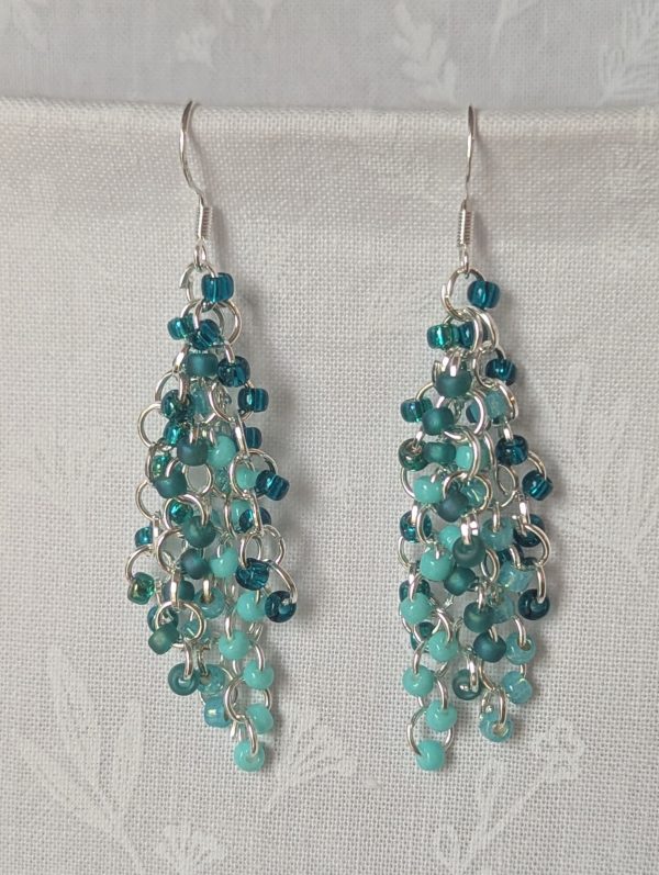 Ocean Depth Earrings featuring 45 glass beads in five teal shades and textures, connected with silver jump rings and sterling silver hooks.